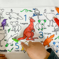 A child colours a reusable silicone HeyDoodle mat of Aussie animals—kangaroo, emu, platypus, koala, kookaburra; two markers nearby.