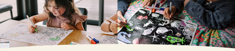 Two children engaged in drawing activities with art supplies on a table.