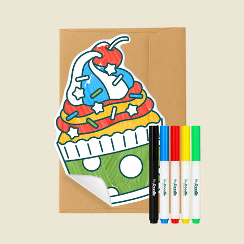 Cupcake-shaped Reusable Gifting Card™ with and envelope and five markers on a beige background
