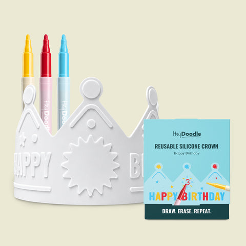 A white silicone HeyDoodle Australia Happy Birthday wearable and reusable colouring crown featuring embossed stars and a sun, accompanied by three markers and a blue square product box.