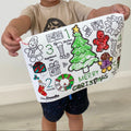 A child holds a HeyDoodle Jingle Bells silicone mat, featuring festive doodles to colour: tree, gingerbread, gifts, candy canes & numbers.
