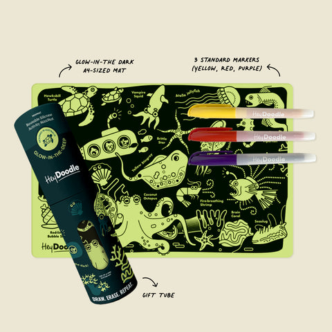 The HeyDoodle Glow-in-the-deep Mini is a silicone, glow-in-the-dark sea creature colouring mat with yellow, red, and purple markers in a gift tube on beige; labels show this reusable kids' set.