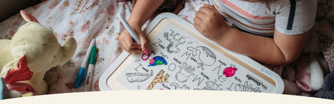 Child coloring on a mini mat on her bed