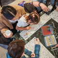 Family of four, including two adults and two children, engaged in colouring activities on a marble countertop.